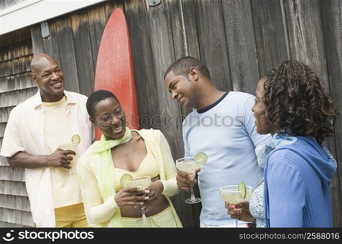 Two couples holding glasses of cocktail and standing together