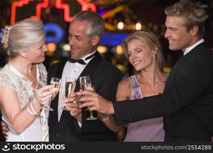 Two couples in casino toasting champagne smiling (selective focus)