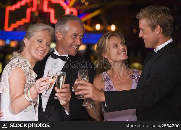 Two couples in casino toasting champagne smiling (selective focus)