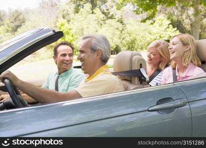 Two couples in convertible car smiling