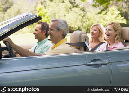 Two couples in convertible car smiling