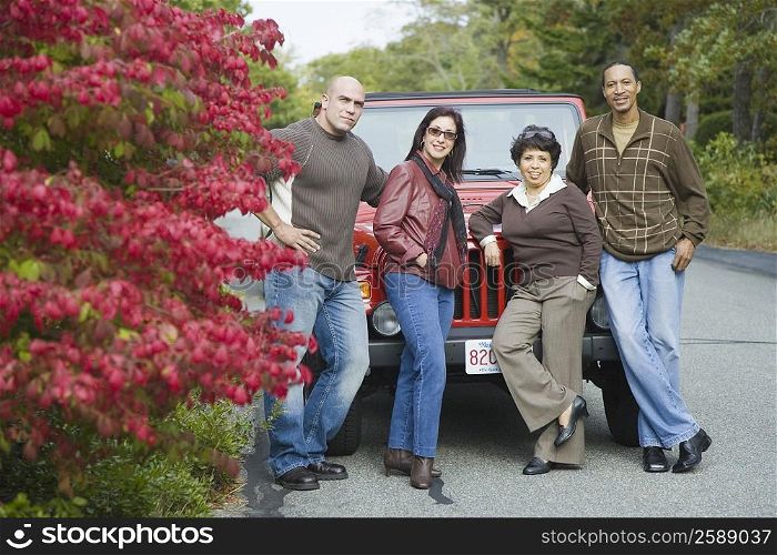 Two couples leaning against a jeep