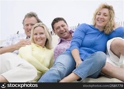 Two couples lying on the beach and smiling