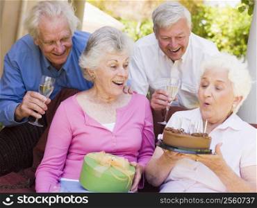 Two couples on patio with cake and gift smiling
