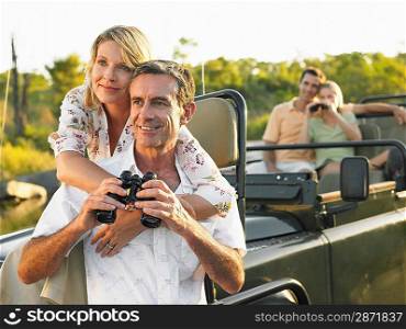 Two couples on trip one sitting in jeep using binoculars