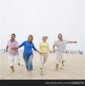 Two couples running on the beach with holding their hands