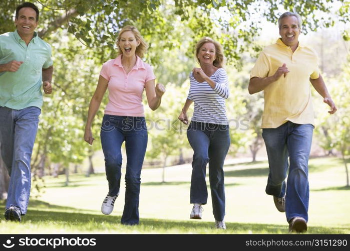 Two couples running outdoors smiling