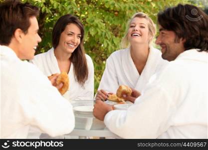 Two couples sharing a joke over breakfast in the garden