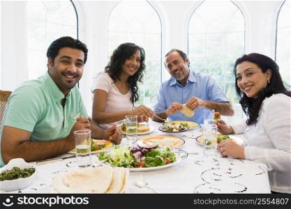 Two couples sitting at dinner table smiling (high key)