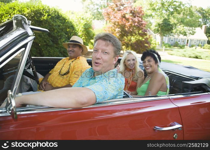 Two couples sitting on a convertible car