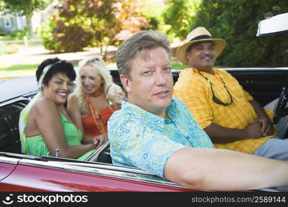 Two couples sitting on a convertible car