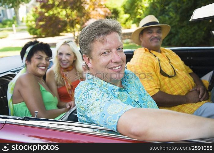 Two couples sitting on a convertible car