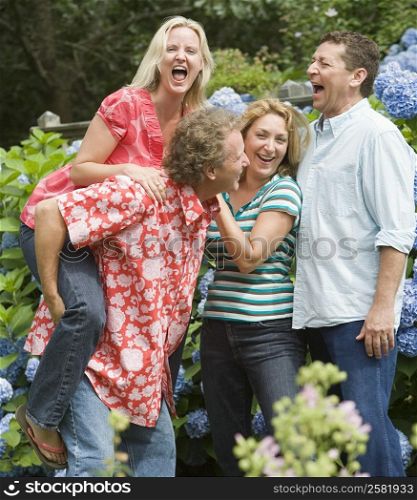 Two couples standing together and laughing in a park