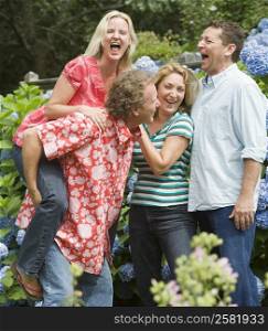 Two couples standing together and laughing in a park