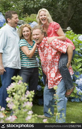 Two couples standing together and laughing in a park