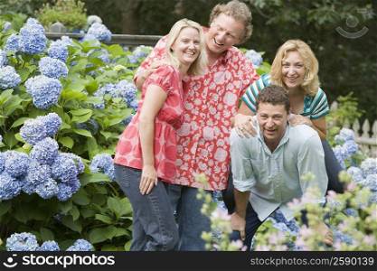 Two couples standing together and smiling in a park
