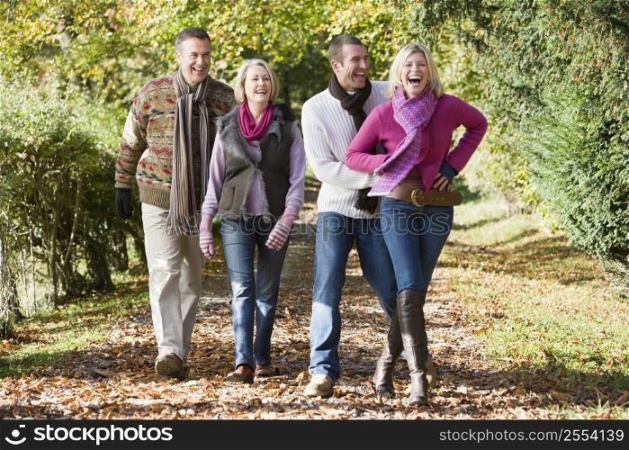 Two couples walking on path outdoors smiling (selective focus)