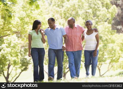 Two couples walking outdoors arm in arm smiling