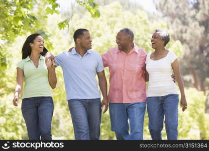 Two couples walking outdoors arm in arm smiling