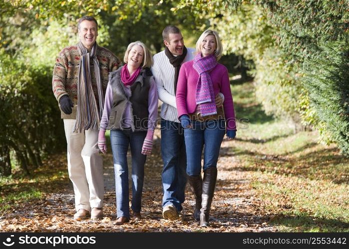 Two couples walking outdoors in park and smiling