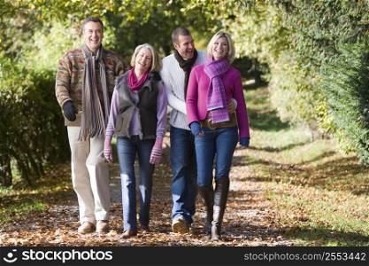 Two couples walking outdoors in park and smiling