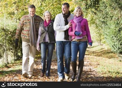 Two couples walking outdoors in park smiling
