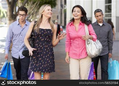 Two Couples With Bored Men Carrying Partners Bags