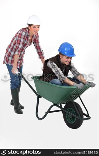 two craftswomen having fun with a wheelbarrow