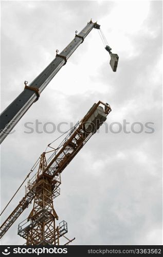Two cranes assembly on sky background