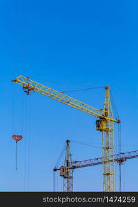 Two cranes with a light blue sky background. Construction site. Old construction equipment.