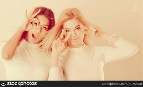 Two crazy girls playing around together.. Friends people fashion concept. Two crazy girls playing around together. Young ladies have white blouse. Women posing in funky way.