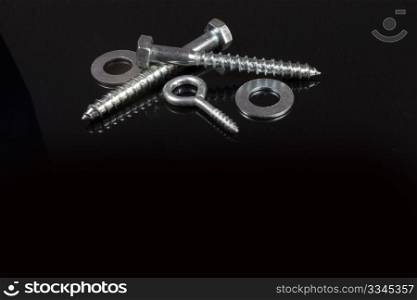 two crossed screws and washers on a black background