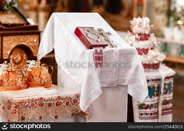 Two crowns the weddings intended for ceremony in orthodox church. Orthodox wedding accessories Holy Bible and silver cross.. Two crowns the weddings intended for ceremony in orthodox church. Orthodox wedding accessories Holy Bible and silver cross