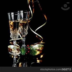 Two crystal glasses of champagne and golden serpentine isolated on a black background, with space for text