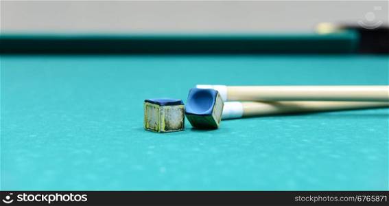 Two cue and two chalk on a billiard table
