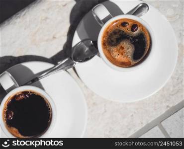 Two cups of aromatic coffee standing on an empty table. View from above, outdoor, close-up. Vacation and travel concept. Two cups of aromatic coffee standing on an empty table