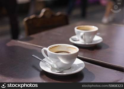 Two cups of coffee on a table outside in the street