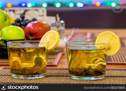 two cups of green tea with lemon and fruit on the table