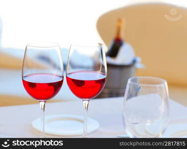 two cups of red wine and bottle in background on ice bucket