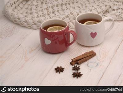 two cups of tea with lemon and scarf on wooden boards. two cups of tea and a scarf