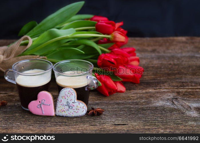 Two cups of Valentines day coffee with fresh red tulips  on wooden table with copy space. Valentines day coffee