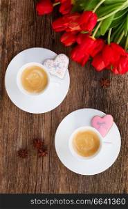 Two cups of Valentines day coffee with fresh tulips on wooden table, top view. Valentines day coffee