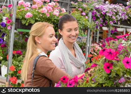 Two customer woman choose colorful flowers in garden center smiling