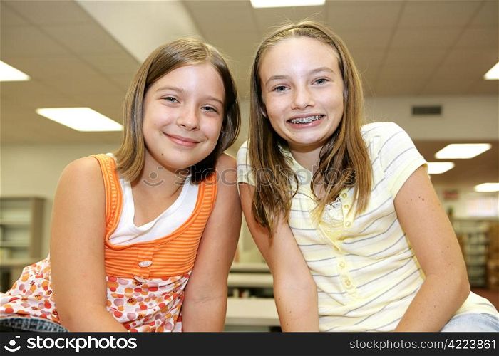 Two cute adolescent girls in the school library.