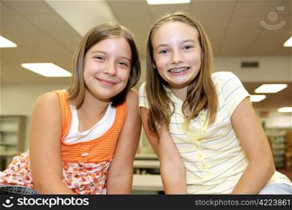 Two cute adolescent girls in the school library.