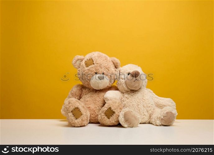 two cute brown teddy bears sitting on a yellow background, childrens toy