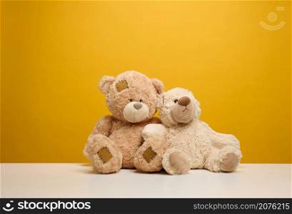 two cute brown teddy bears sitting on a yellow background, childrens toy