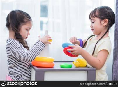 Two cute Caucasian girls playing toys together in home. Kids development and leisure concept. Home sweet home and Happy family theme.