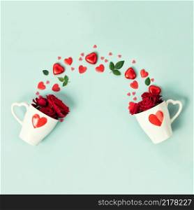 Two cute cups with roses, chocolate and red hearts on blue background, top view, flat lay. Valentine&rsquo;s day, Wedding, Anniversary concept