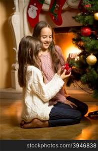 Two cute girls sitting on floor and decorating Christmas tree